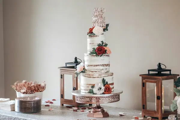 کیک عروسی : کیک سه طبقه سفید با تزئین گلهای سفید و قرمز روی پایه مسی رنگ