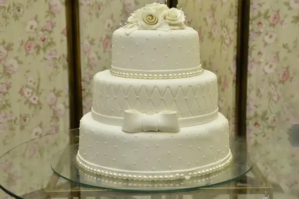 کیک عروسی : کیک سه طبقه سفید با مروارید و پاپیون تزئین شده