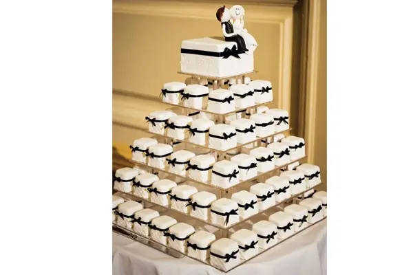 کیک عروس بصورت تکه های کوچک با پاپیون مشکی در چند طبقه