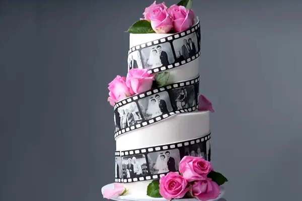 کیک عروس سه طبقه با حلقه فیلم لابراتوار شامل عکسهای عروس و داماد و گلهای صورتی